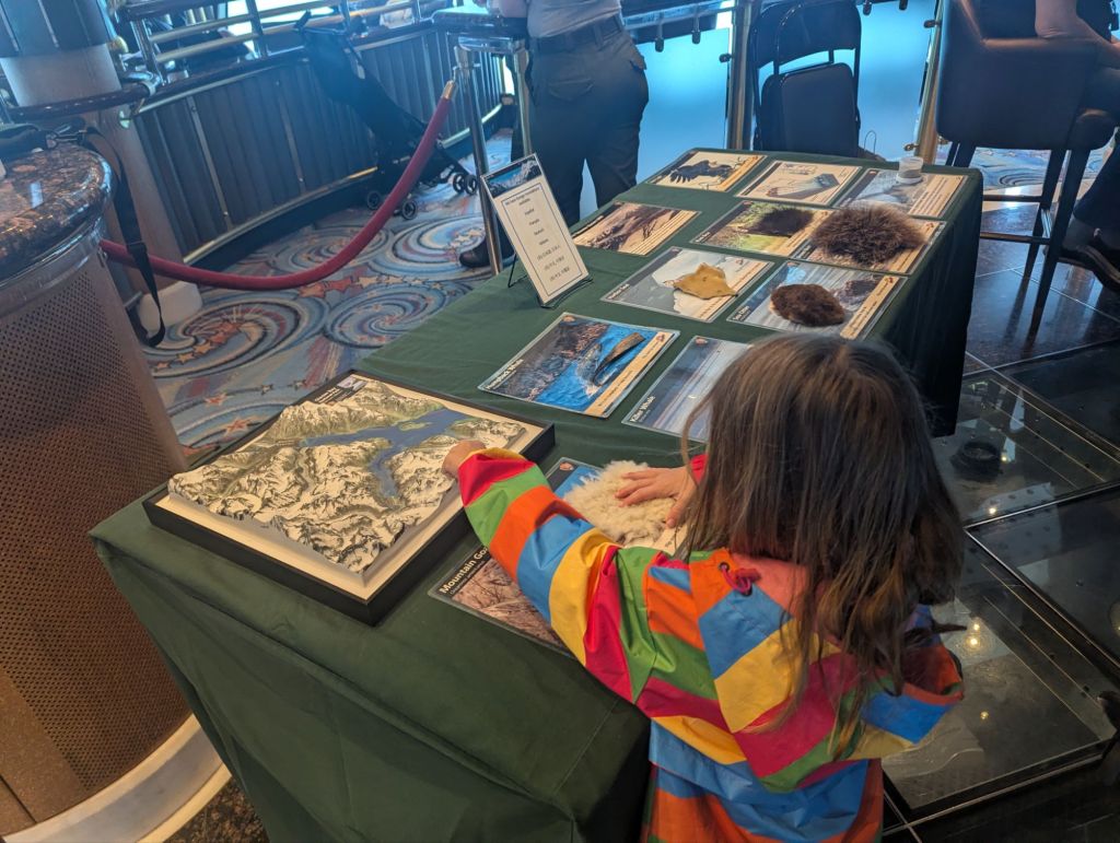 child in rainbow raincoat touches topographical map of national park